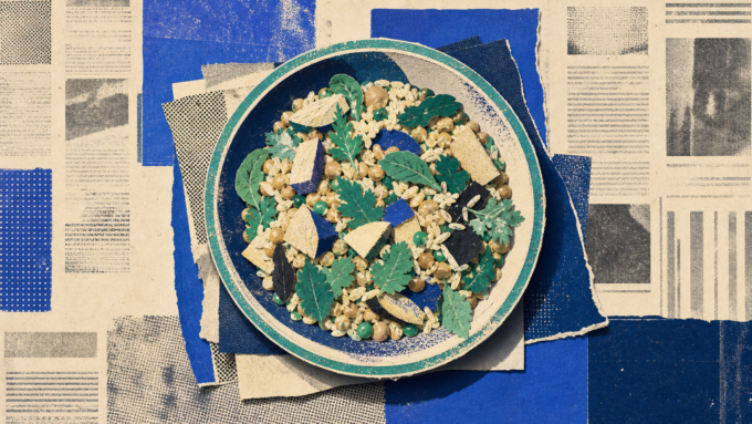 Top-down royal-blue newsprint collage showing one generously filled bowl of food centered on warm off-white newspaper paper, symbolizing falling global hunger.